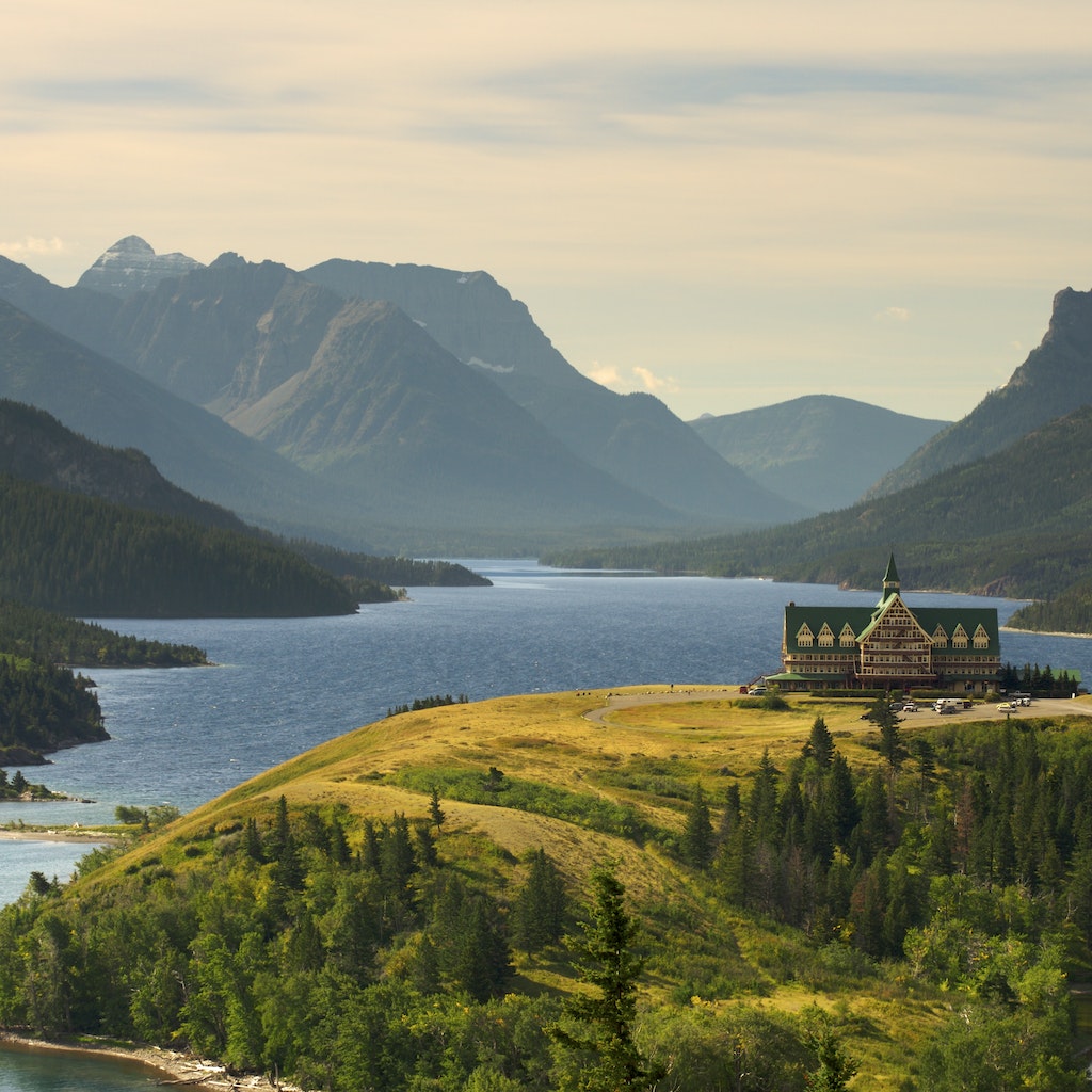 A view of Upper Waterton Lake during the early morning with a landmark Hotel building on a peninsular in the foreground.