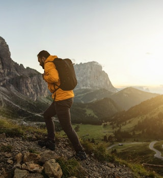 Man mountain hiking at sunset on the Dolomites: post pandemic outdoor adventure
