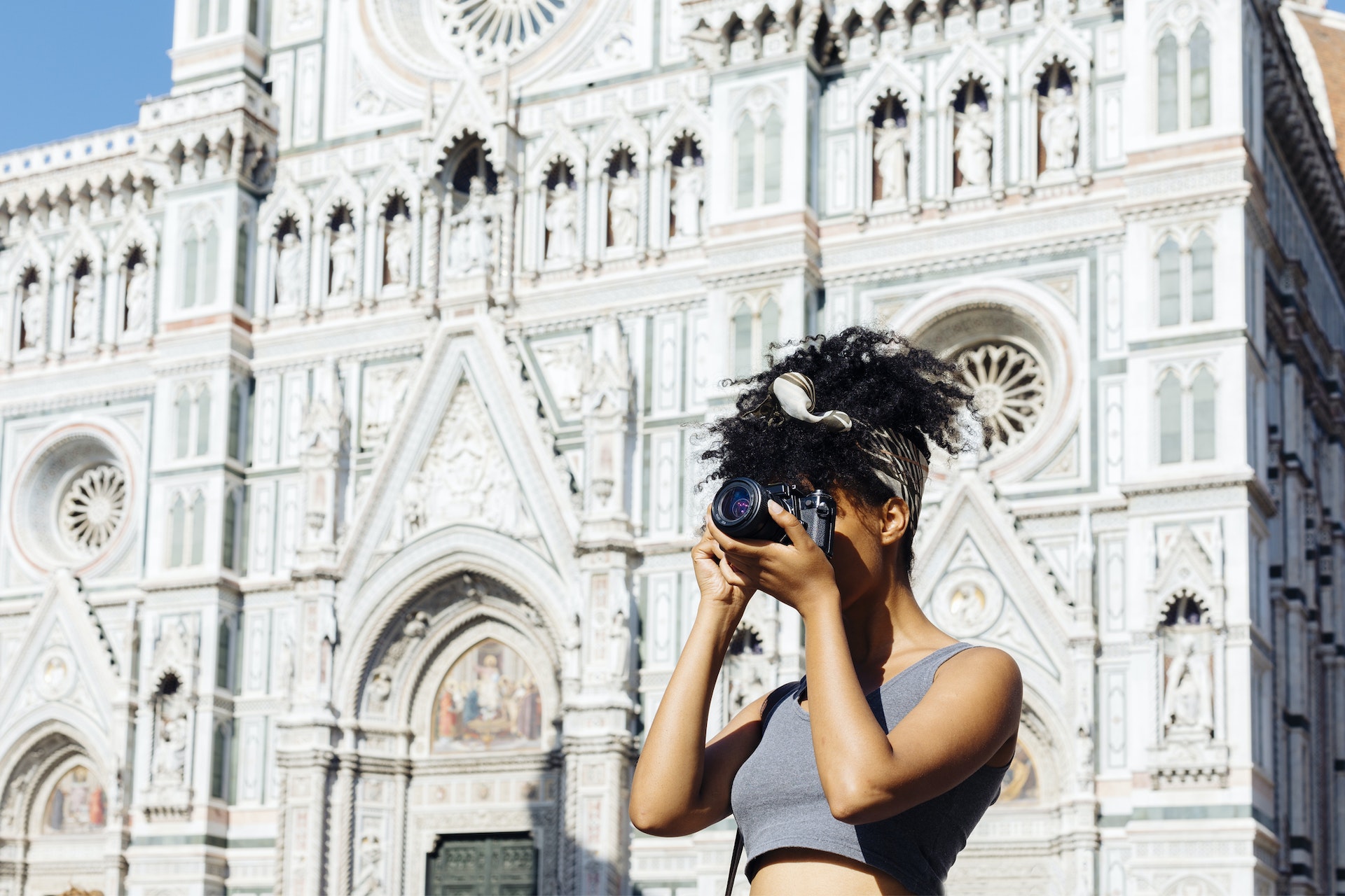 Young woman taking photo with camera in front of cathedral, Florence, Italy