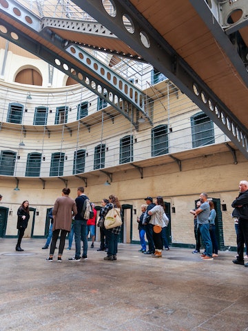 August 2019: A tour group on the floor of the Victorian main hall in the Kilmainham Gaol, a former prison which is now a museum. 