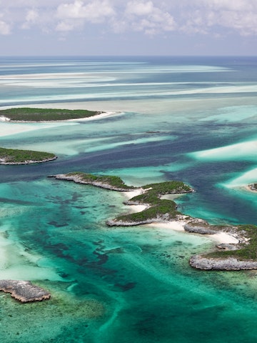 Aerial view of the islands, beautiful sandy bottom and green water contours of the Exumas in the Bahamas.